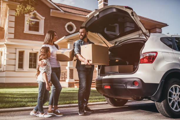 A family loading boxes into the car at home — moving day.